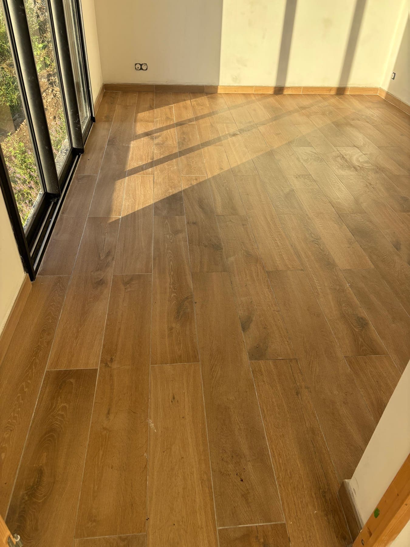 Carrelage imitation bois dans une pièce traversée par la lumière du matin