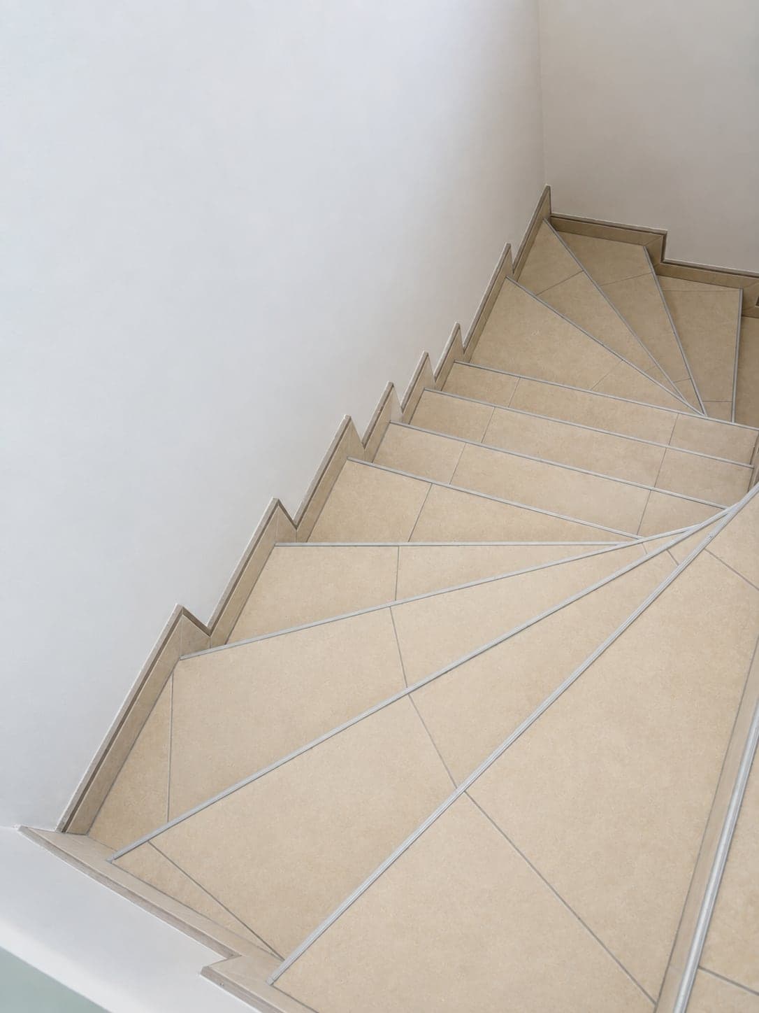 Marches balancées d'un escalier carrelé, coupes d'onglet et nez de marche en profilé