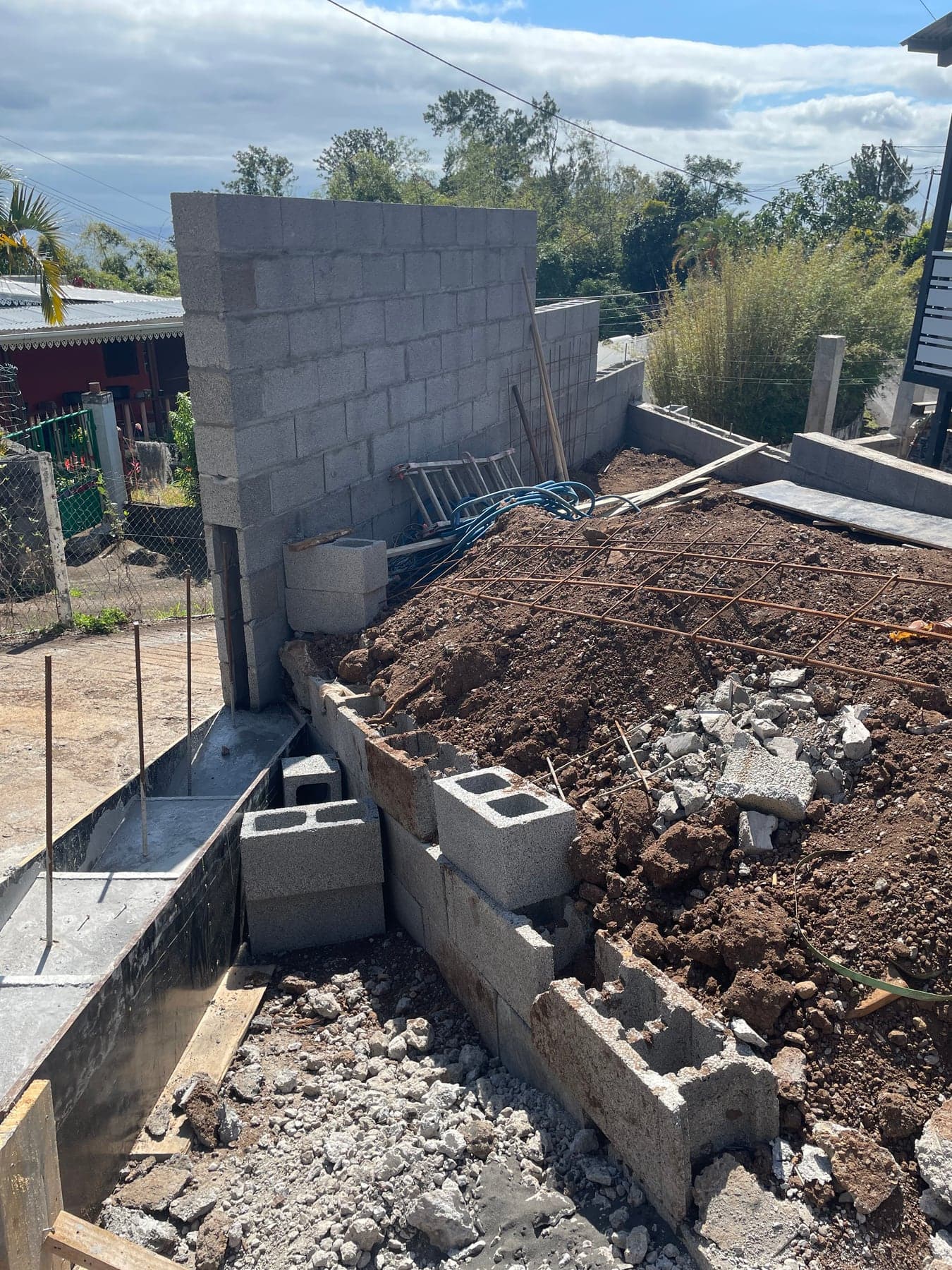 Fondations et première rangée de parpaings du mur de soutènement en cours de montage