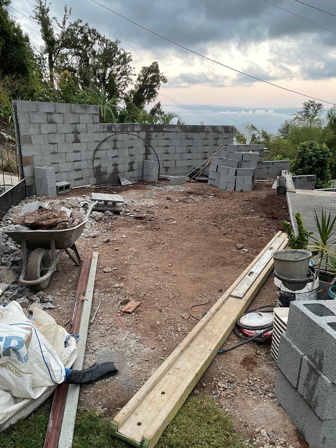 Avant travaux : mur de soutènement en parpaing en cours de montage et terrain nu