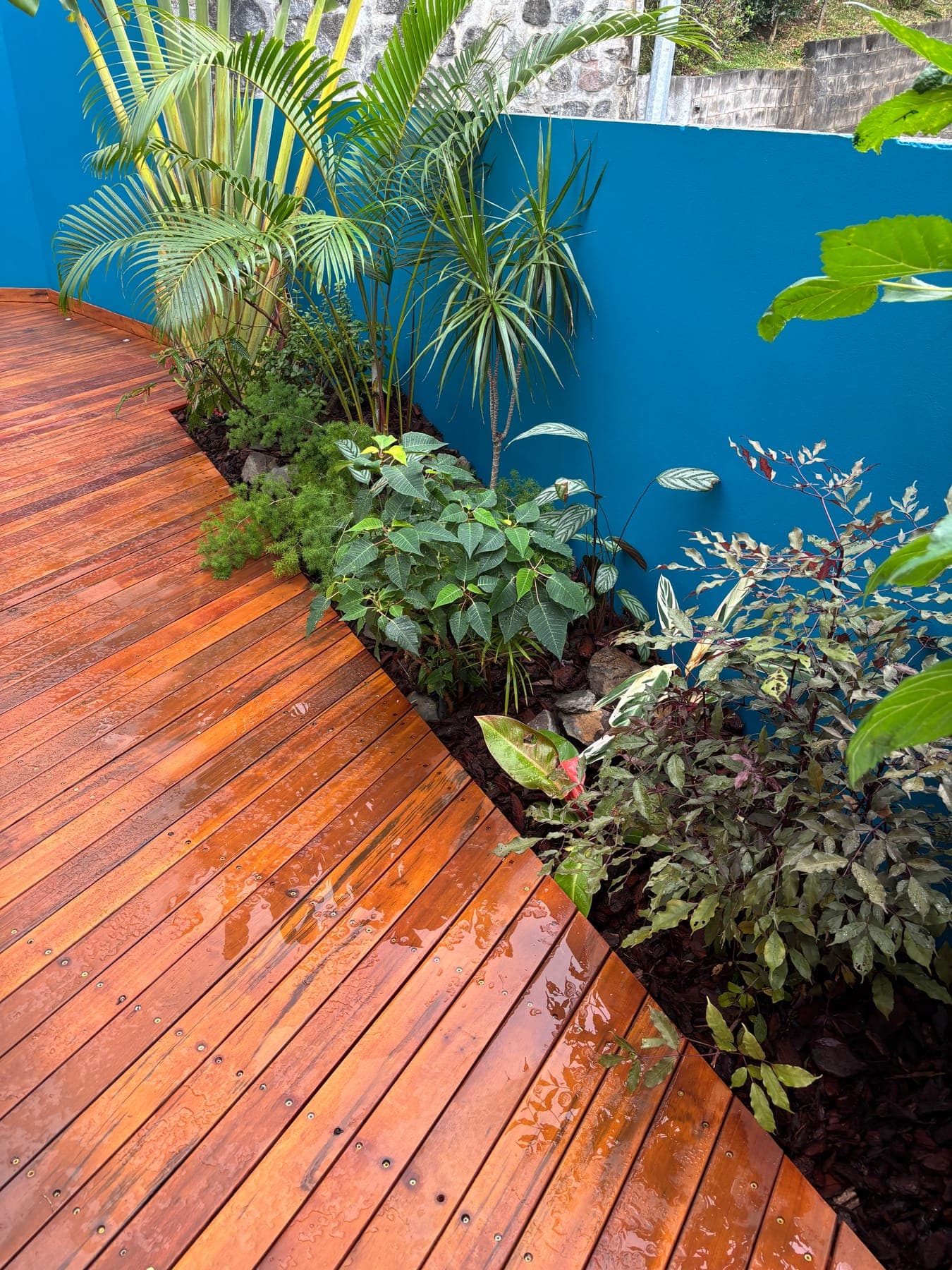 Lames de terrasse en bois épousant la courbe d'un massif planté